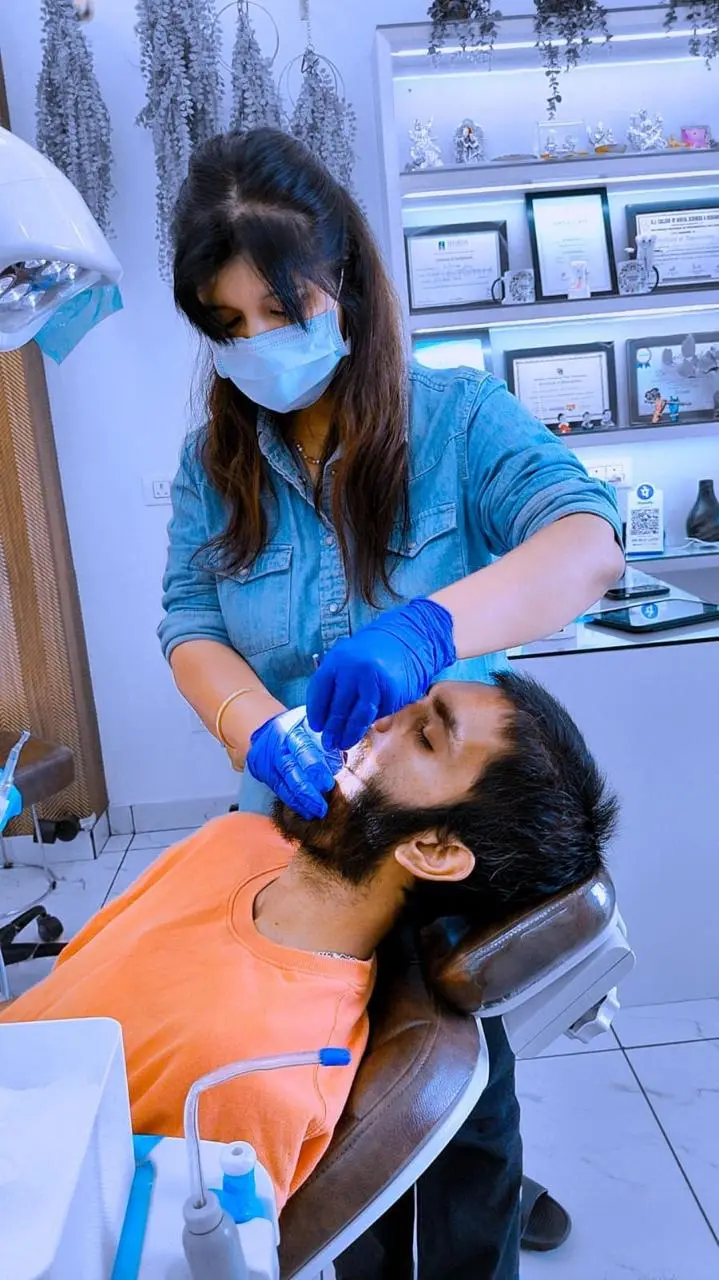 Dr. Arti Kumari treating a patient, certificates on the wall behind